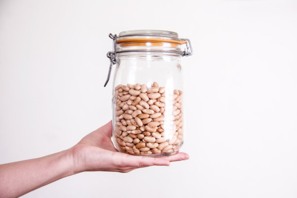 一只手拿着装满干斑豆的玻璃罐图片下载