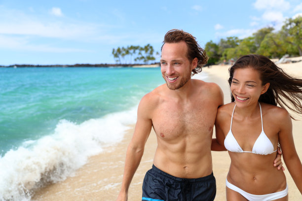 性感的晒黑的跨种族夫妇走在沙滩上图片下载