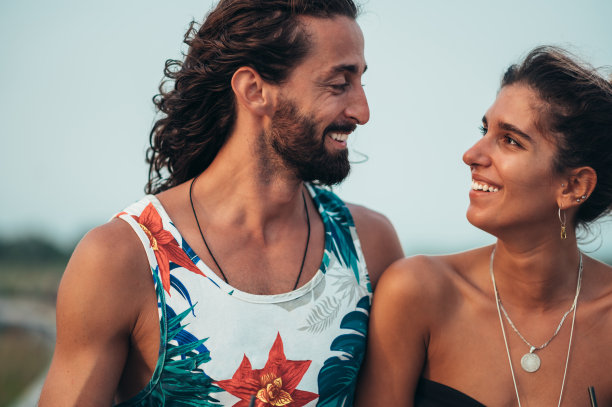 迷人的年轻夫妇带着酒精鸡尾酒在海滩上散步图片下载