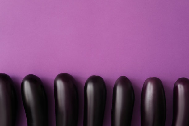 生熟的茄子放在紫色的底色上，平铺。空间的文本图片下载