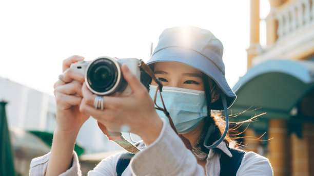 年轻的亚洲女性背包客戴着口罩用相机拍照图片下载
