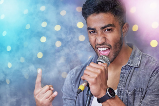 剪裁的肖像英俊的年轻男性摇滚歌手在舞台上唱歌图片下载