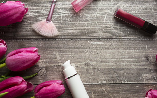 女性办公桌工作空间与化妆品，口红和郁金香花木制背景。平躺，俯视图图片下载