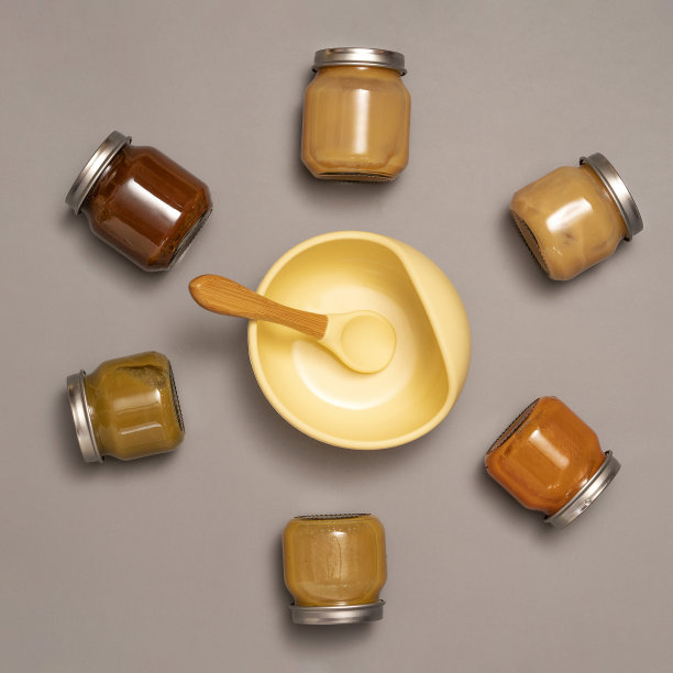 婴儿食品配料。装满婴儿泥的罐子，硅胶碗和勺子。婴儿喂养时间概念。午餐时间图片下载