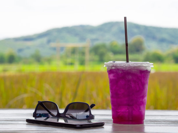 太阳镜的特写，电话和草药水在白色的木制桌子上图片下载