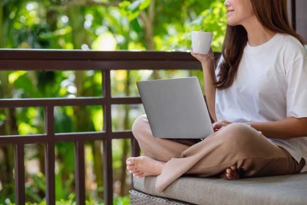 一个年轻女人喝咖啡的特写图像，而使用笔记本电脑工作或学习在家里在线图片下载