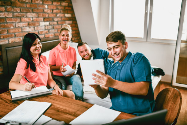 微笑的男性向学校的朋友展示如何在一起学习时解决复杂的数学问题图片下载