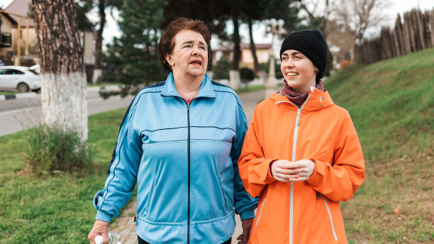 一位老奶奶和一个成年孙女在公园里散步的照片。一家人在公园散步。国际老年人日图片下载