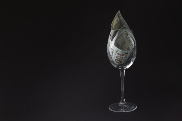 玻璃是完整的百元钞票。一张美元钞票躺在一个空酒杯里。图片下载