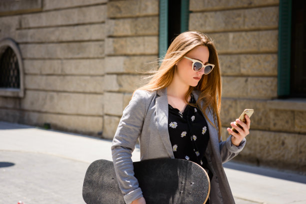 手持滑板，手持手机的商业女孩图片下载