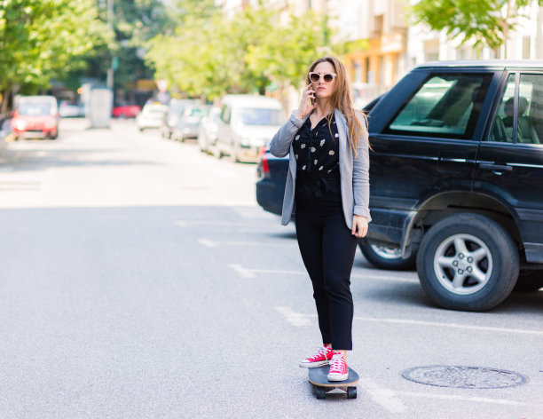 年轻的女商人在玩滑板图片下载