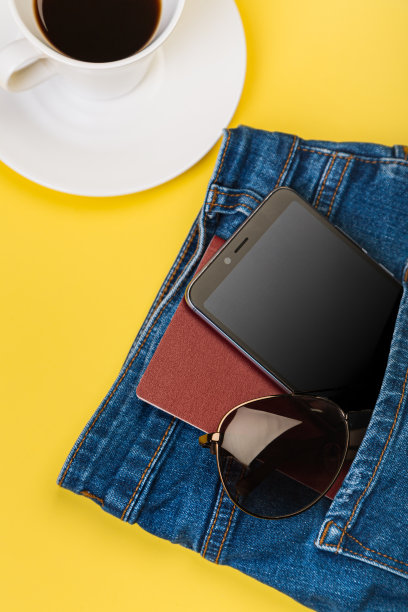 手机、眼镜和护照从牛仔裤口袋里探出来，旁边放着一杯咖啡图片下载
