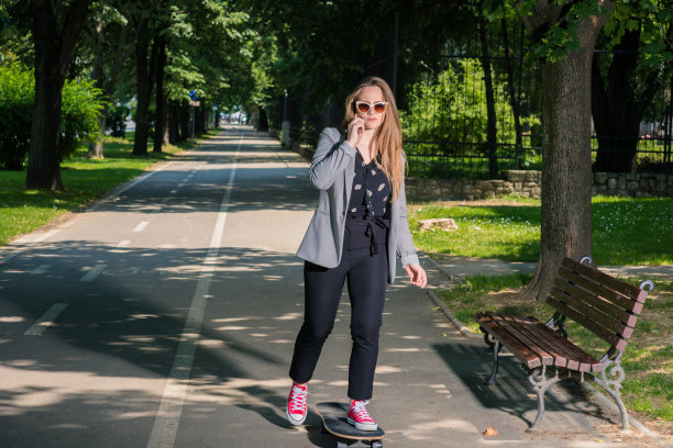 踩滑板的人站在公园的小路上图片下载