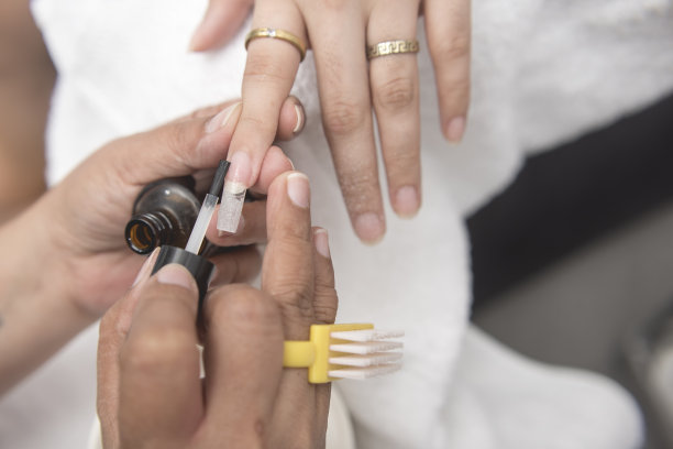 美甲师将一层指甲油涂在食指和延伸的指甲上。在沙龙或客厅里。图片下载