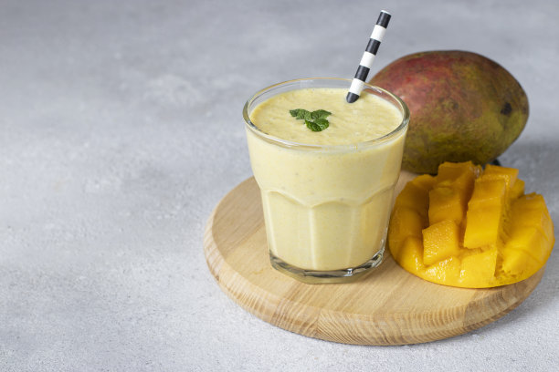 Lassi芒果玻璃在灰色背景的木板上。印度健康阿育吠陀冷饮芒果，复印空间图片下载