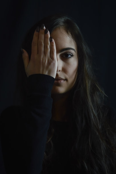 一个美丽的年轻女子的黑白特写肖像，她用一只手隐藏了她的半张脸图片下载
