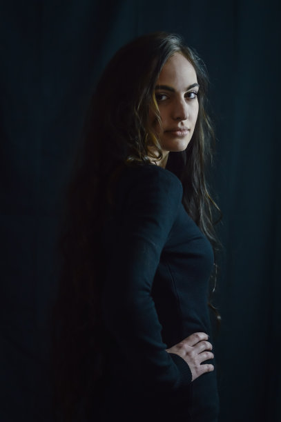 一个美丽的年轻意大利女人的肖像与非常长的棕色头发谁与她的手在她的臀部看起来在一个严肃和挑衅的方式图片下载