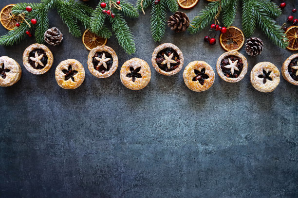 形象节日圣诞设计海报边界云杉针，红色浆果，松果，干橙柑橘水果片，糕点星星详细的盖子，节日圣诞甜点脆皮糕点与甜肉馅，灰色背景，复制空间图片下载