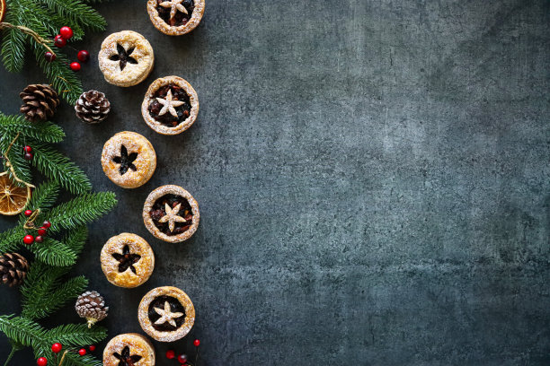 形象节日圣诞设计海报边界云杉针，红色浆果，松果，干橙柑橘水果片，糕点星星详细的盖子，节日圣诞甜点脆皮糕点与甜肉馅，灰色背景，复制空间图片下载