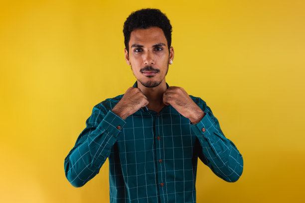 一个穿着西装的黑人在画室里被黄色的背景孤立起来。孤立的商人，充满戏剧性的光芒。图片下载