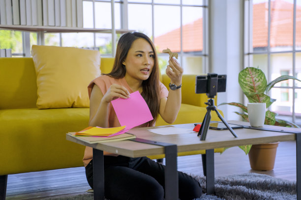 一名年轻女子正在工作，通过视频会议制作折纸。图片下载