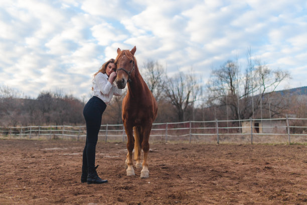 在农场上，一位年轻的白人妇女抱着她的棕色马图片下载