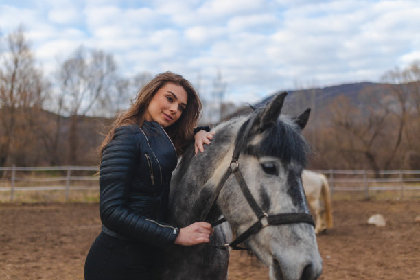 一个年轻的女人抱着她的黑白马在农场里图片下载