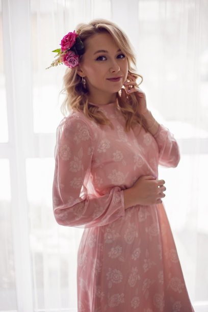 一幅时尚的金发女人的肖像站在窗口，她穿着粉红色的裙子，头上插着一朵玫瑰图片下载