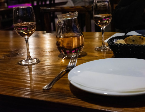 餐厅餐桌上有玻璃瓶和玻璃杯，小篮子里有大蒜面包作为开胃菜图片下载