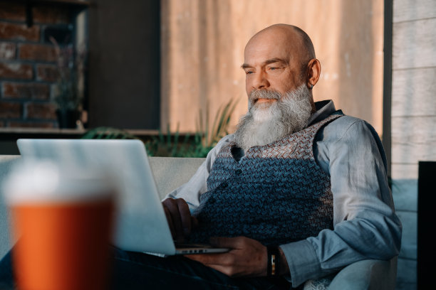 老男人拿着一杯酒，用他的笔记本电脑图片下载