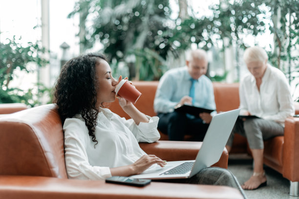 年轻的女商人带着外卖咖啡坐在商务中心的大厅里图片下载