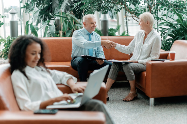 商人和女商人在办公室大厅里互相握手致意图片下载