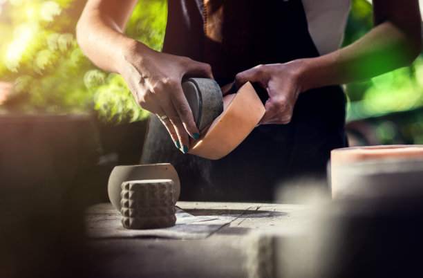 近距离拍摄手工艺人的手在她的工作室制作装饰混凝土花瓶。图片下载
