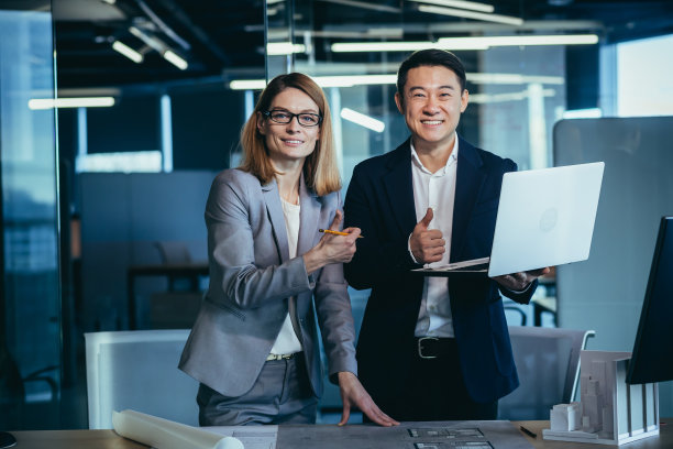 两个建筑师团队，看着摄像机，欣喜地微笑着完成的项目，保持拇指肯定图片下载