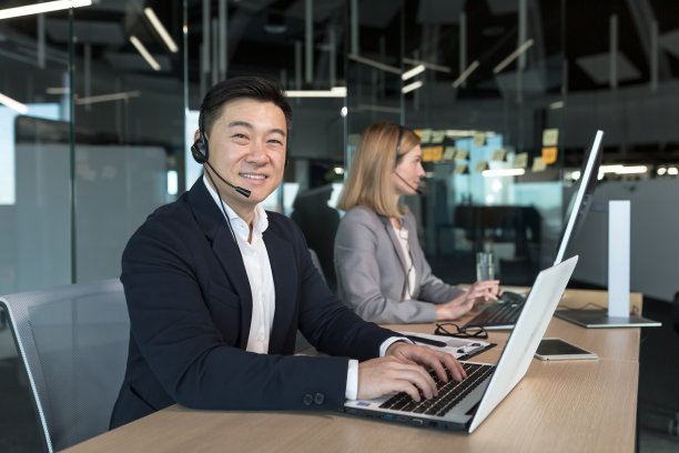 穿着商务服装的亚洲人的特写，呼叫中心职员微笑着看着摄像机，商人用电脑进行视频通话，戴上耳机图片下载