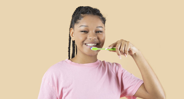 漂亮年轻的混血儿女人，棕色背景，拿着牙刷图片下载