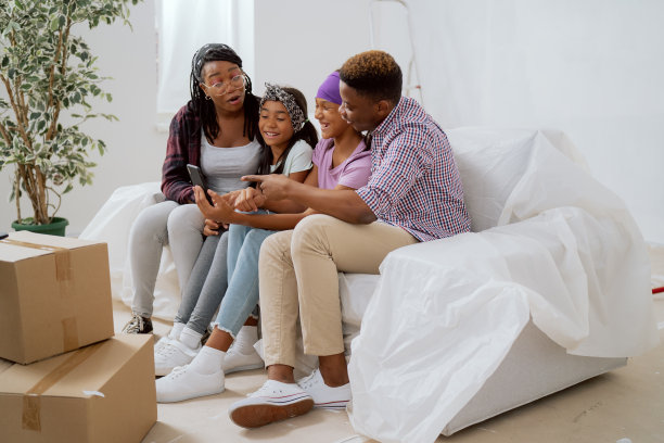 相亲相爱幸福美满的家庭正在装修的公寓里消磨时间，他们在手机上看照片，搞笑的照片，说笑，评论，大笑图片下载