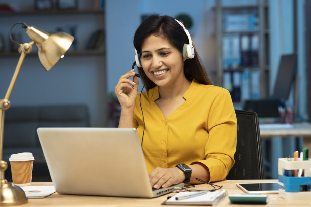 呼叫中心女话务员戴着耳机与客户通话，库存照片图片下载