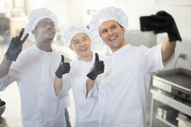 快乐的多种族厨师团队在厨房里一起做饭，用手机自拍图片下载