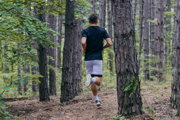 一个有吸引力的男性运动员在森林中奔跑的全长照片图片下载