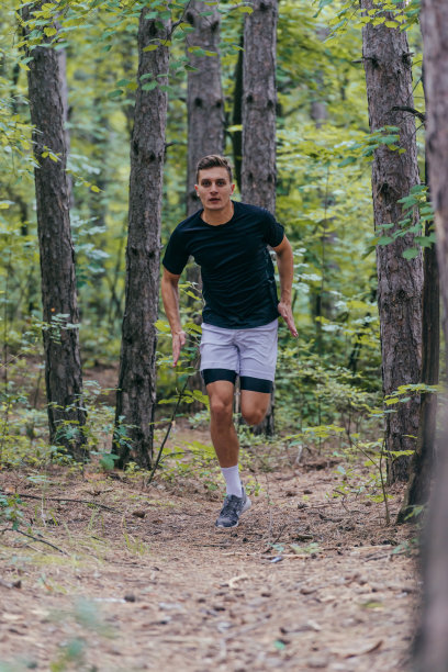 一个有吸引力的男性运动员在森林中奔跑的全长照片图片下载