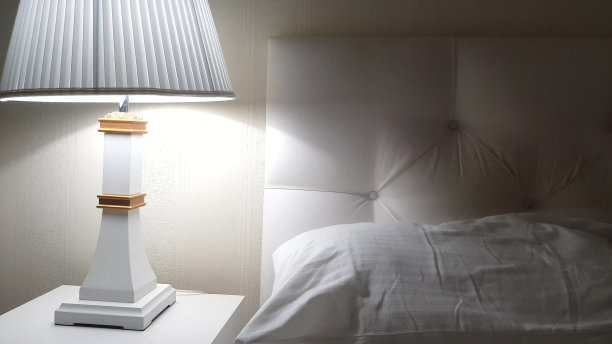 豪华酒店床，准备睡觉，床头柜上有台灯和干净的白色床单，床上有枕头，晚上图片下载