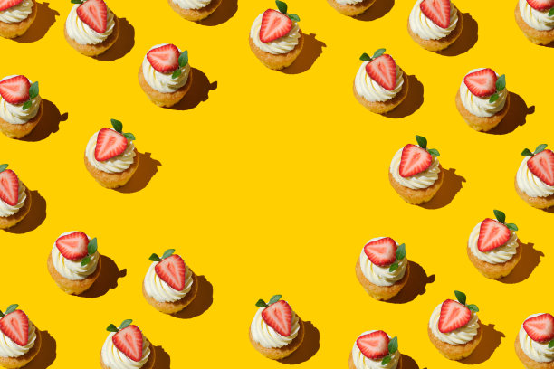 用黄色背景上的草莓和奶油制作的家庭饼干图案。文字复制空间，上面有大草莓的纸杯蛋糕。用草莓和奶油图案重复自制饼干。平的风格。图片下载