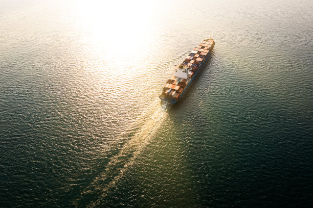 集装箱货轮在海上运输：傍晚阳光下的国际商业物流图片下载