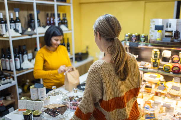 白人女售货员把装着产品的纸袋递给女顾客图片下载