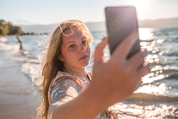 千禧一代的大尺寸模特在海滩上自拍的肖像图片下载