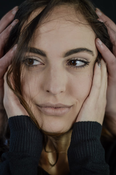 健康和自尊-一个美丽的年轻女子的肖像，双手放在脸颊上，另外两只手放在她的头上图片下载