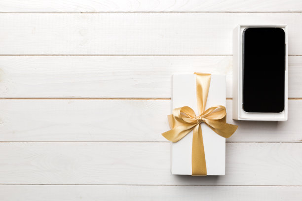 打开礼盒与金色丝带和智能手机的颜色背景，俯视图。空白开盒包装样板，为您的设计-品牌样板图片下载