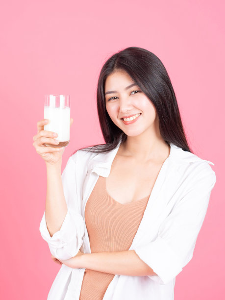 亚洲可爱的女孩感到快乐喝牛奶为健康在早上粉红色的背景-生活方式美丽的女人图片下载