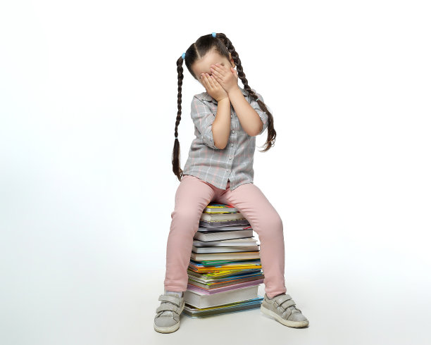 扎着辫子的小女孩坐在一大堆书上，用手捂着脸图片下载